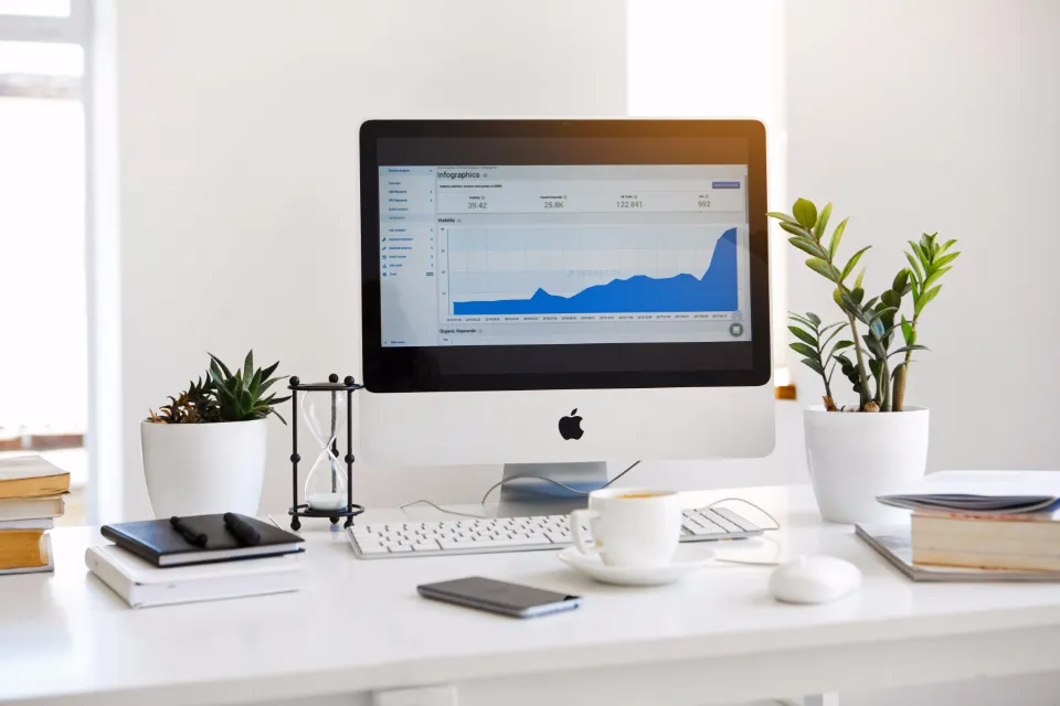 Beyaz bir masada web sitesi istatistiklerini gösteren bilgisayar ekranı
