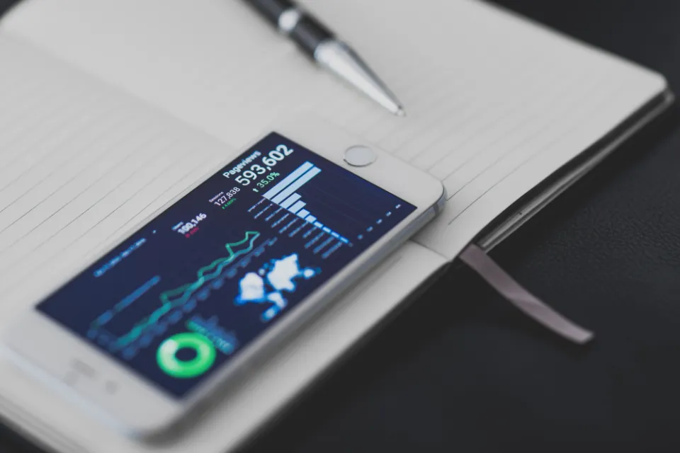 Defterin üzerinde reklam performans grafiklerini gösteren akıllı telefon