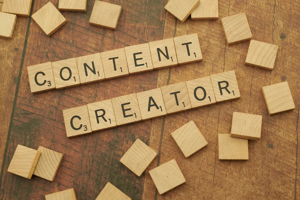 Ahşap masa üzerinde CONTENT CREATOR yazan harf blokları
